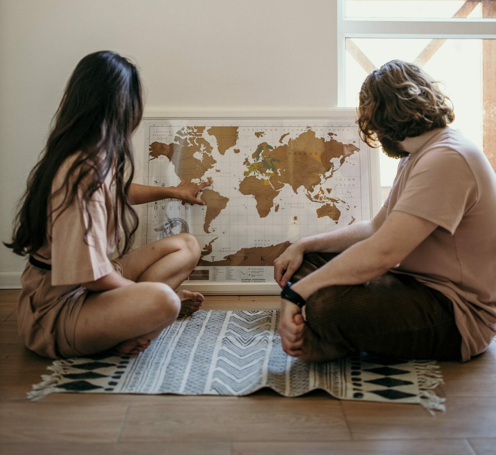 Young couple sitting on the floor, studying a map of the world and discussing International Family Law implications