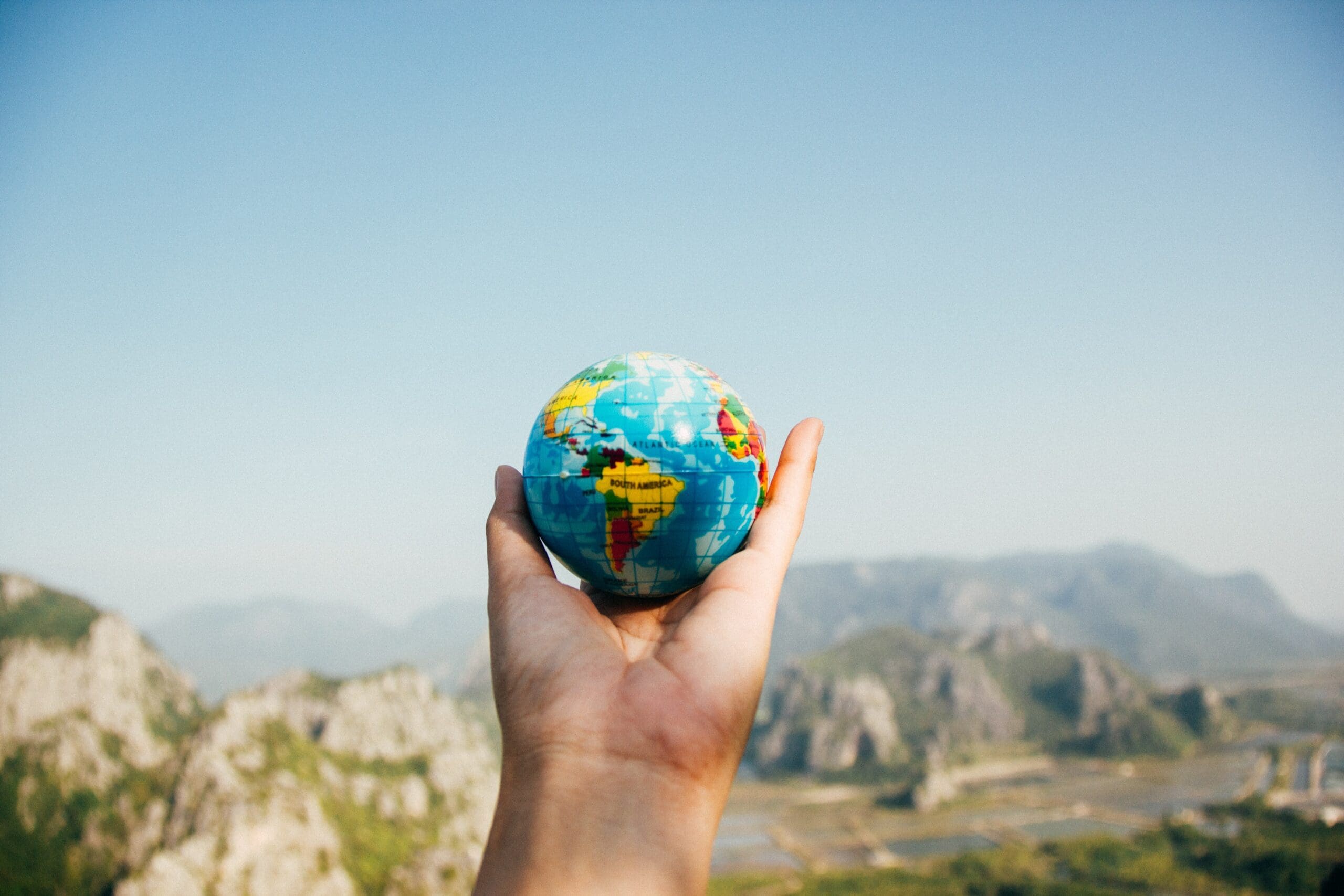 Hand holding a spherical globe with majestic mountains in the background, symbolising the vast scope of International Family Law.