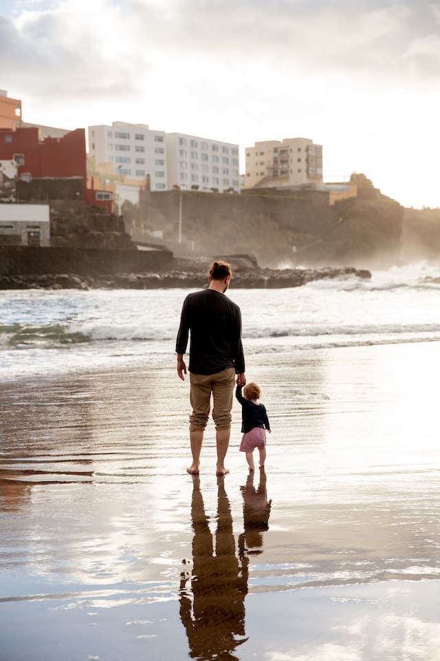 Father and toddler enjoying a serene walk on the beach