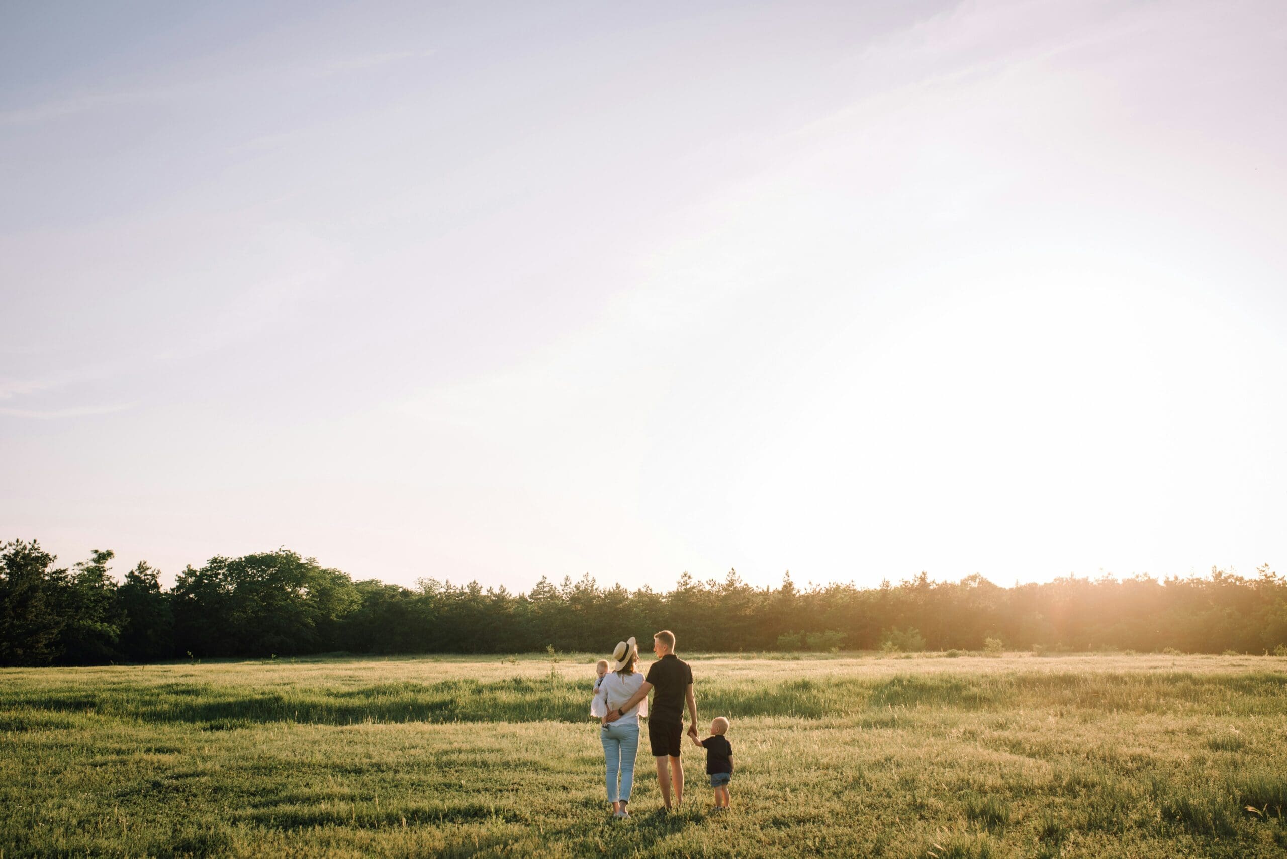 A family embracing while standing in an open field at sunset, symbolising the warmth and unity that can come from the adoption process in Australia.
