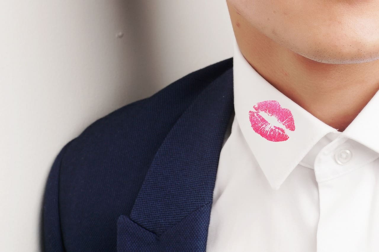 Red lipstick kiss mark on a white shirt collar, symbolising marital infidelity issues leading to divorce.